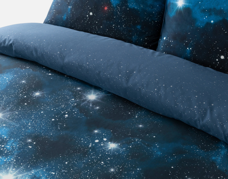 Folded top edge on our Supernova Duvet Cover to show its shining starry surface and lighter navy sky reverse.