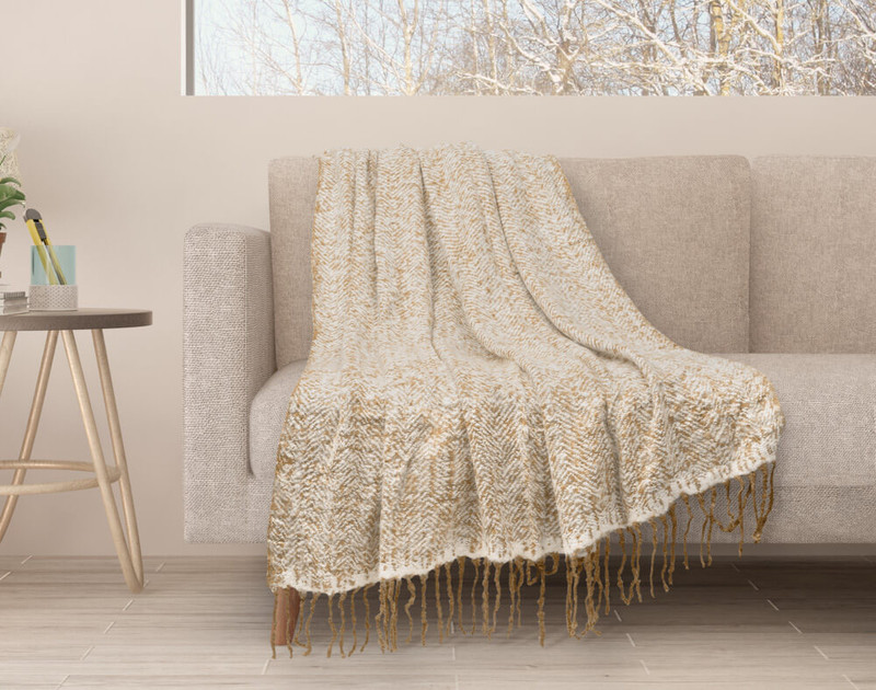 Our Oat Mix Herringbone Knit Fringe Throw draped over a couch.