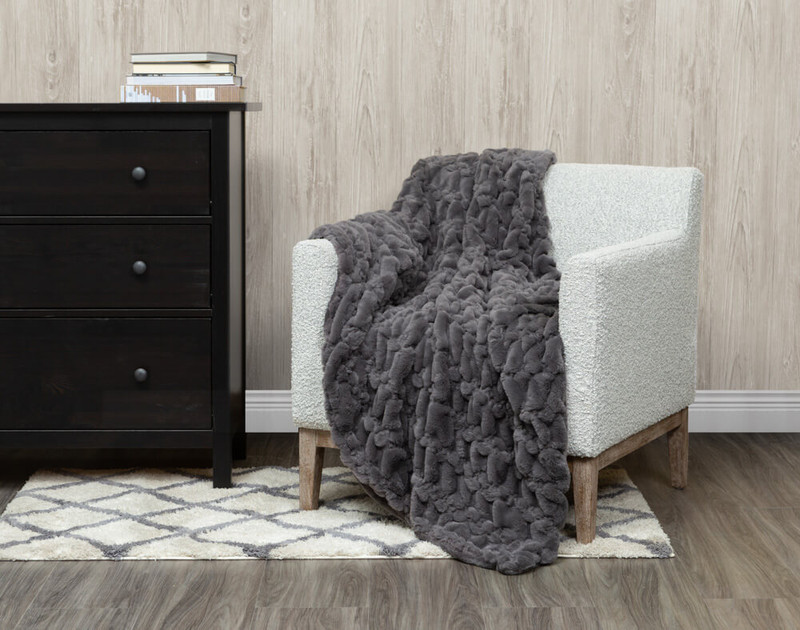 Our Carved Faux Fur Throw in Graphite Grey, draped over a chair.