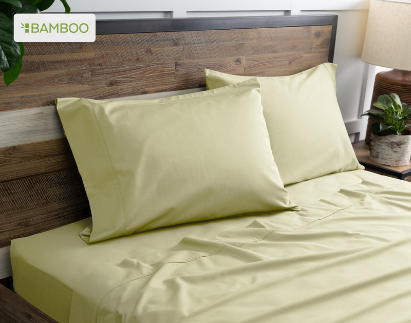 Two of our Bamboo Cotton Pillowcases in Elm Green resting on a wooden bed with coordinating sheets.