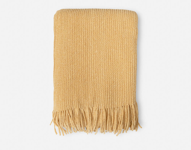 Our Chenille Throw in Gold folded into a square, with its fringe edge draping down the bottom.