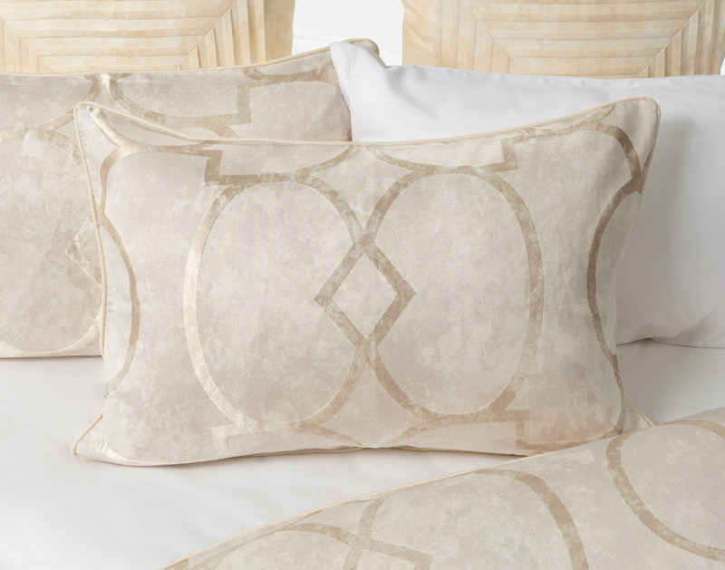 Our Boulevard Pillow Sham sitting over a half-open white bed against other matching pillows.