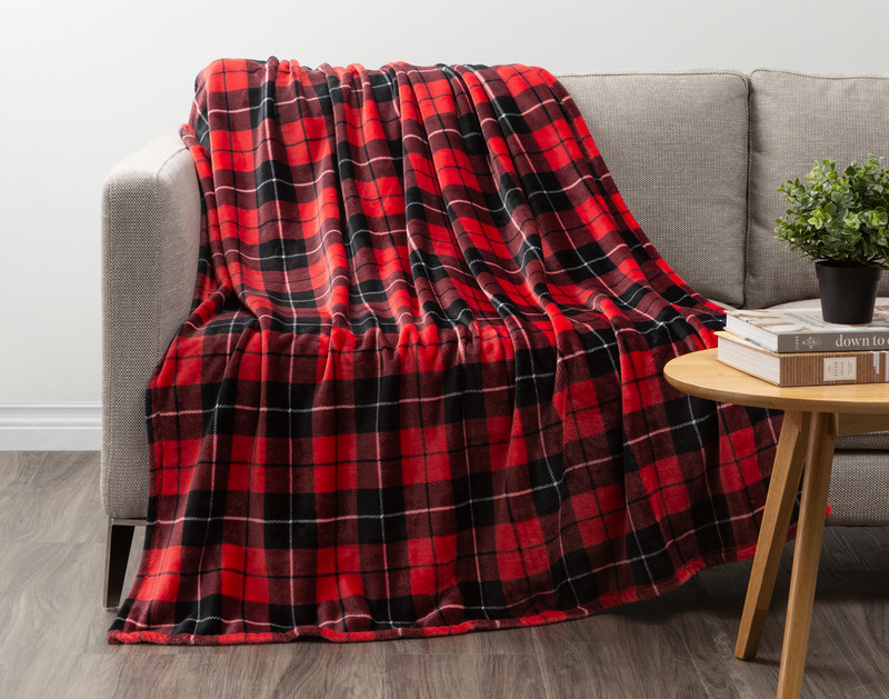 Our Plaid Fleece Throw in Crimson Red draped over a couch in a grey living room.