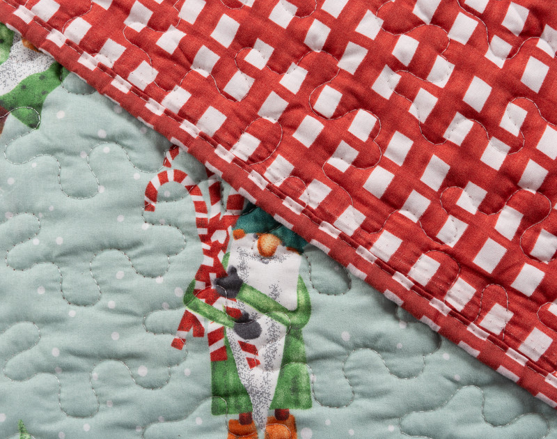 Folded edge of our Santa's Elves Coverlet Set to show its gingham reverse and elf pattern face.