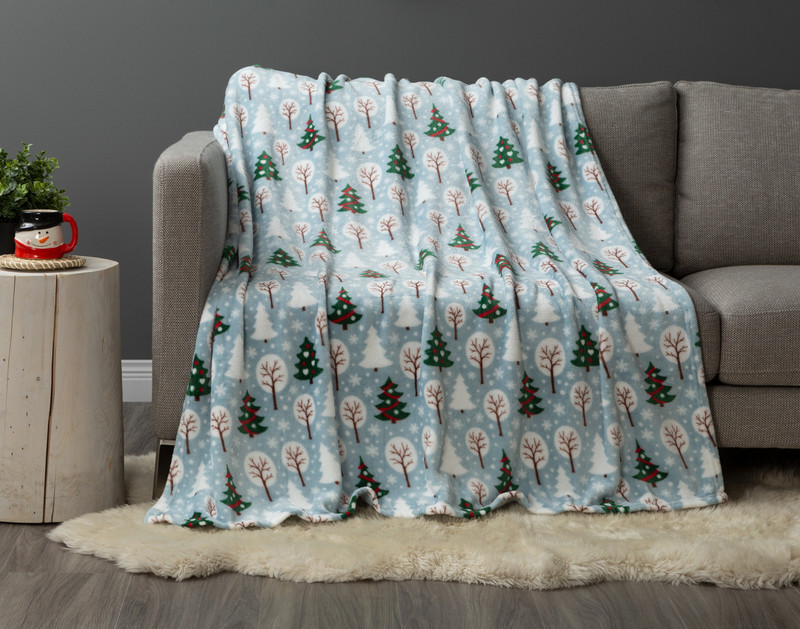 Our Winter Trees Holiday Fleece Throw draped over a couch in a festive living room.
