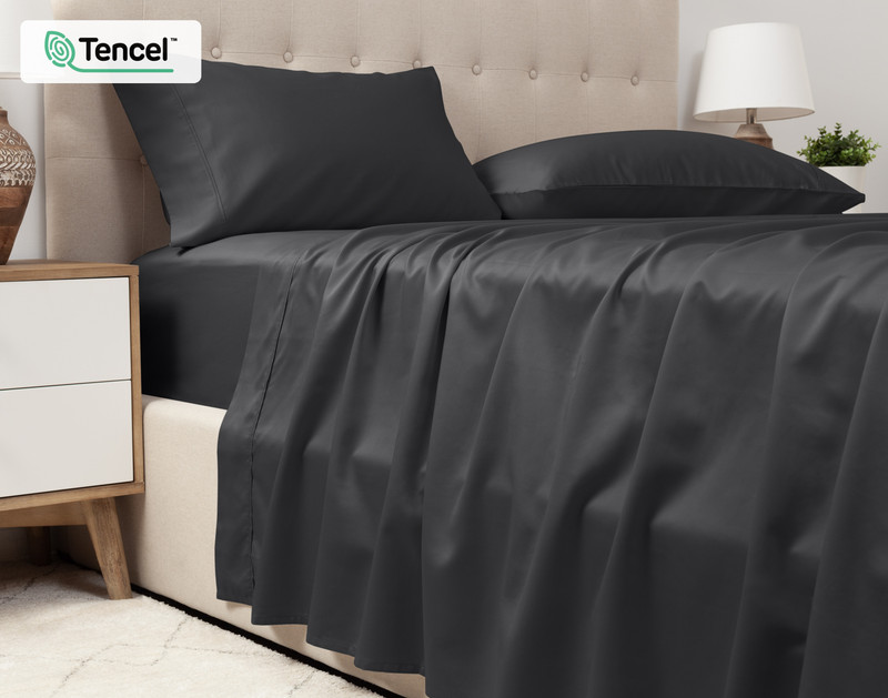 Vue inférieure de notre Eucalyptus Luxe TENCEL™ Lyocell drap ensemble  en Black Pearl pour montrer son drap plat drapé sur le côté d'un grand lit.