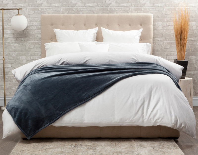 Front view of our Cashmere Touch Fleece Blanket in Sea Storm draped over a tidy white bed.