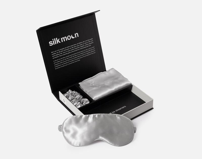Angled view of our unboxed Mulberry Silk Gift Set in Silver featuring a silk eye mask, pillowcase, and scrunchie.