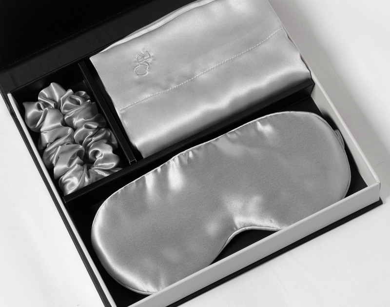 The silk pillowcase, eye mask, and scrunchie of our Mulberry Silk Gift Set in Silver folded in its packaging.