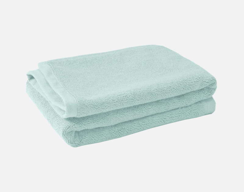 Pile pliée de nos tapis de bain en coton modal de couleur Seafoam sur un fond blanc uni.