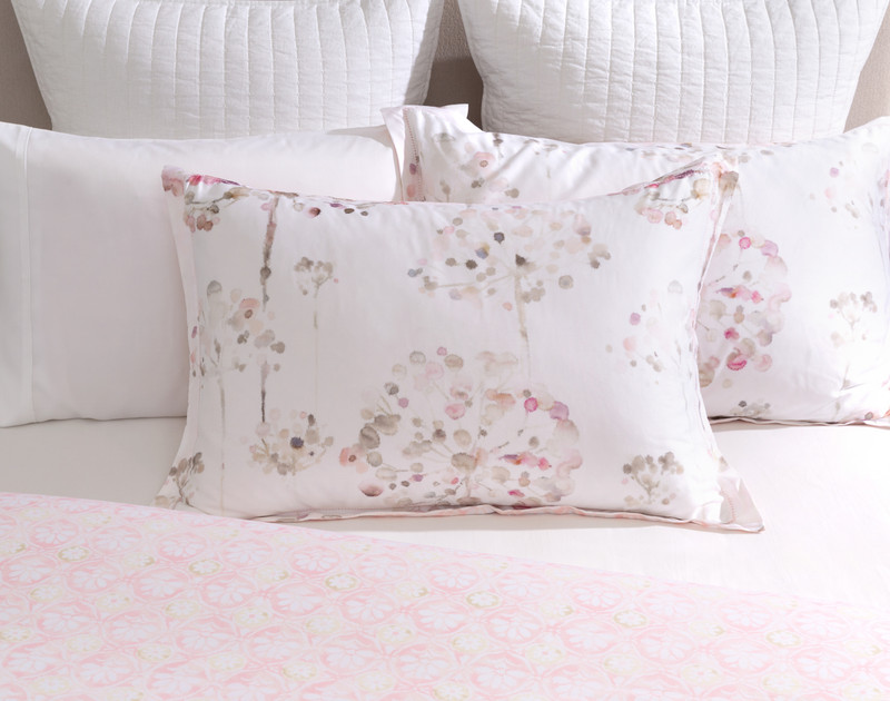 Our Angelica Pillow Sham sitting against coordinating pillow shams over a half-dressed white bed.