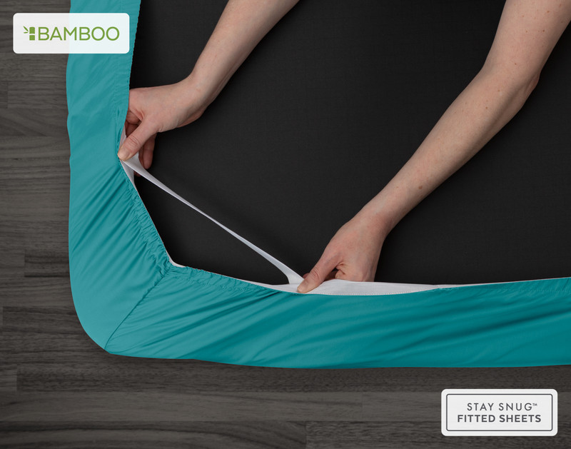 Bottom view of our Bamboo Cotton Fitted Sheet in Reef to show two hands pulling the Snug Fit elastics holding the corner in place over a mattress.
