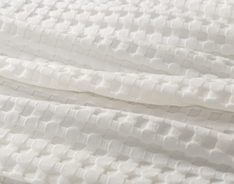 Gros plan sur le tissu légèrement ébouriffé de notre couverture gaufrée Bamboo Cotton en blanc pour montrer la douceur et la légèreté du tissu.