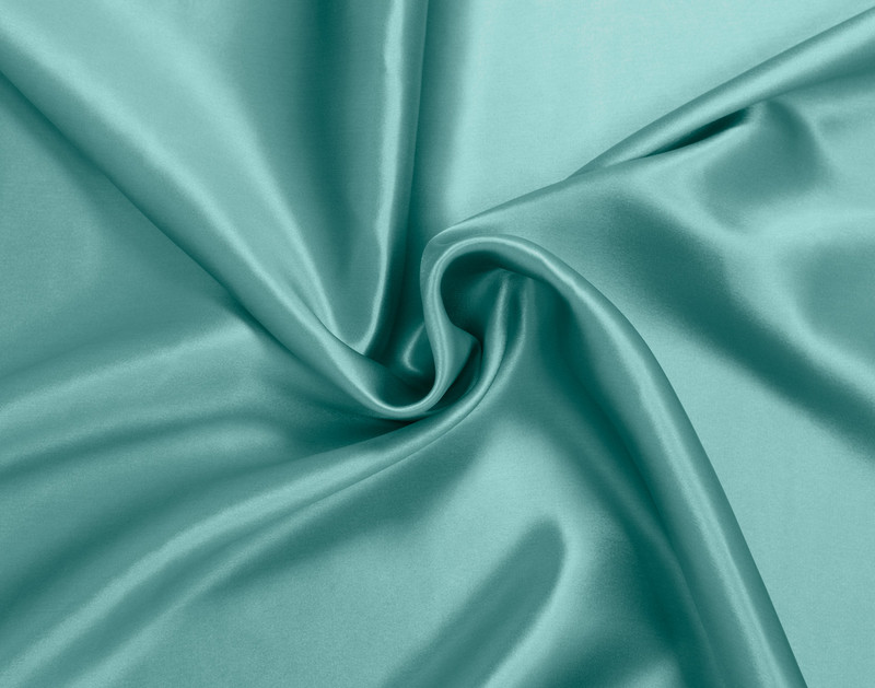 Le tissu enroulé sur notre taie d'oreiller Soie de mûrier en bleu aqua montre sa surface luxueusement lisse.