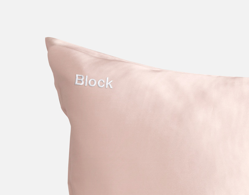 Gros plan sur le coin de notre taie d'oreiller Soie de mûrier en rose blush Pink pour montrer le mot "Block" brodé avec notre fil blanc et la police Block.