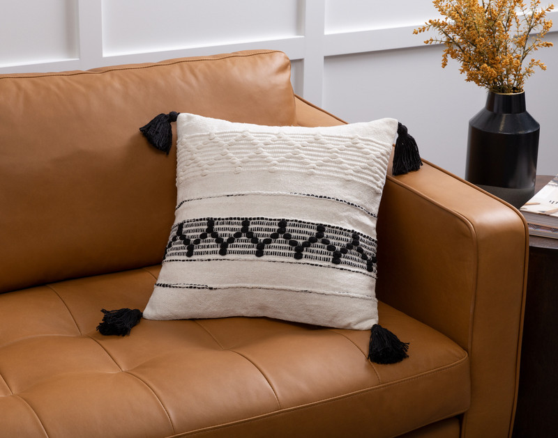 Our Kavi Artisanal Cushion sitting against the corner of a light brown couch.
