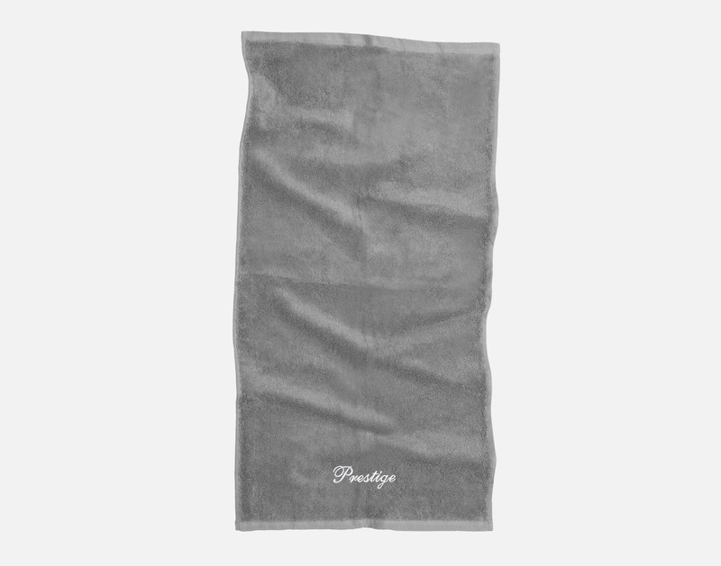 Top view of the hand towel of our Custom Embroidered Towel Set in Grey, featuring the word "Prestige" embroidered in white thread in our cursive Prestige font along its bottom edge.