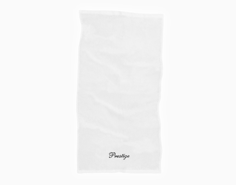 Vue de dessus de l'essuie-mains de notre serviette brodée personnalisée ensemble en blanc, avec le mot "Prestige" brodé en fil blanc dans notre police cursive Prestige le long du bord inférieur.