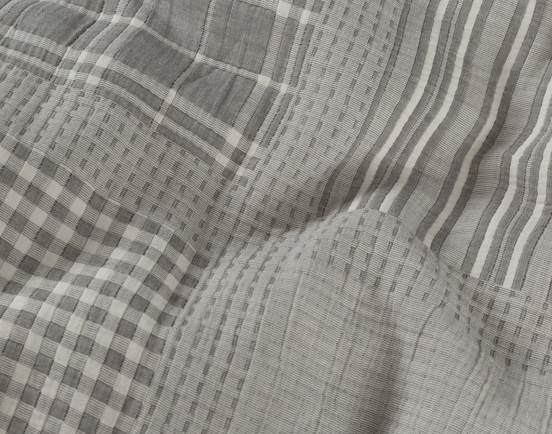 Close-up on some ruffled fabric on our Reid Duvet Cover to show its diverse checkered and lined patch design.