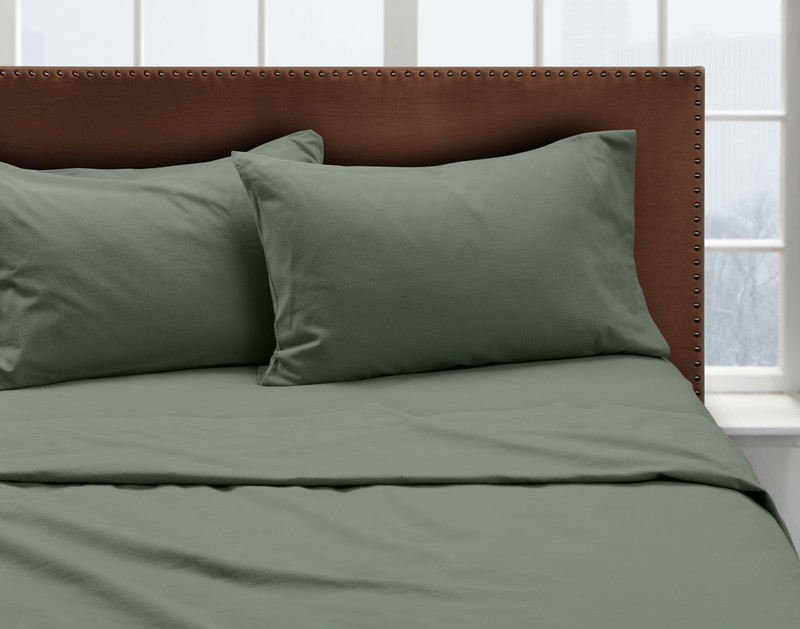 Front view of our Organic Flannel Cotton Sheet Set in Pine Green dressed neatly over a queen bed with queen pillows  in a windowed white bedroom.