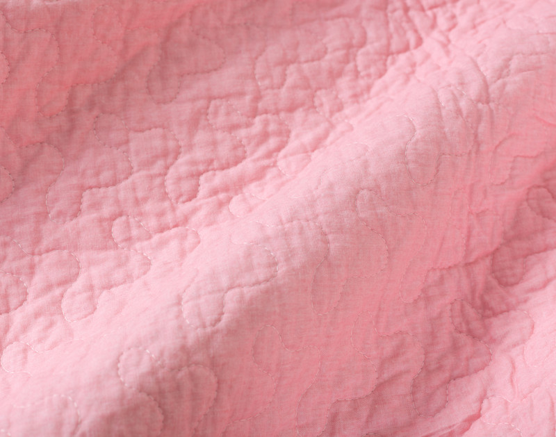 Close-up on the solid blush bubblegum pink backing on our Alora Cotton Quilt Set.