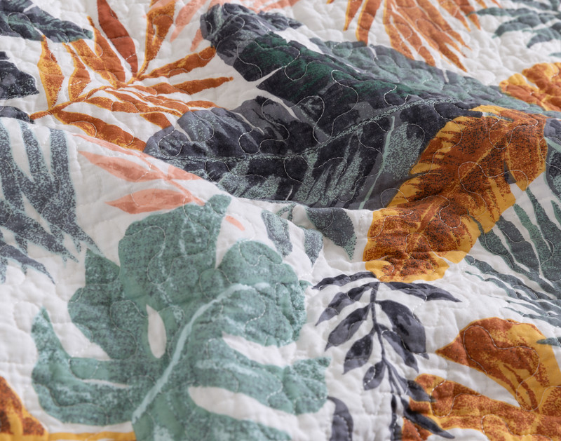 Close-up on the botanical fern design on our Tropics Cotton Quilt Set, featuring blue, green, and copper leaves.