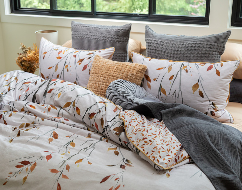 Close-up angled view Saturna Duvet Cover with multiple grey throw blankets and accessory cushions over top.