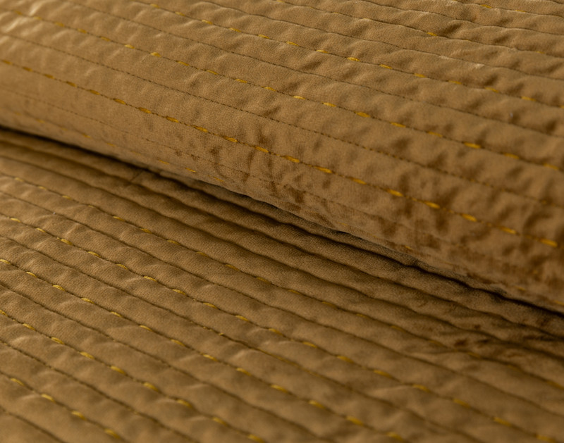 Angled view of the rolled up top edge on our Casimir Quilt Set to show its soft gold colour.