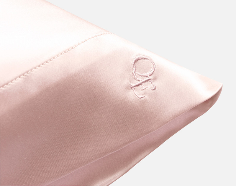 Close-up on the embroidered QE Home logo on the corner of our Mulberry Silk Pillowcase.