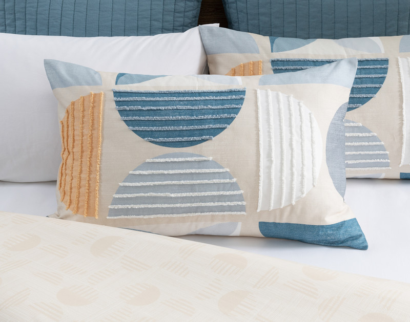 Front view of our Nora Pillow Sham resting on a half-dressed bed with coordinating pillows.