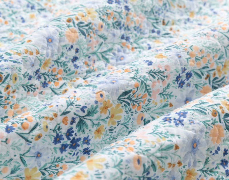 Close-up on the floral garden design on the surface of our Camellia Cotton Quilt Set.