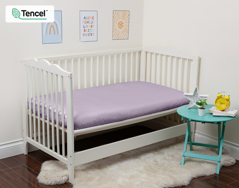 Our Eucalyptus Luxe Crib-Sized Fitted Sheet in Shoreline dressed over a small mattress in an open crib.
