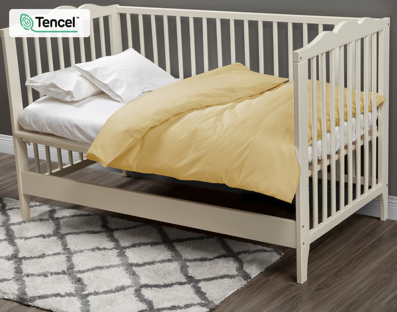 Our BeechBliss Crib-Sized Duvet Cover in Sun Shower dressed over a small white mattress in a cream white crib. 