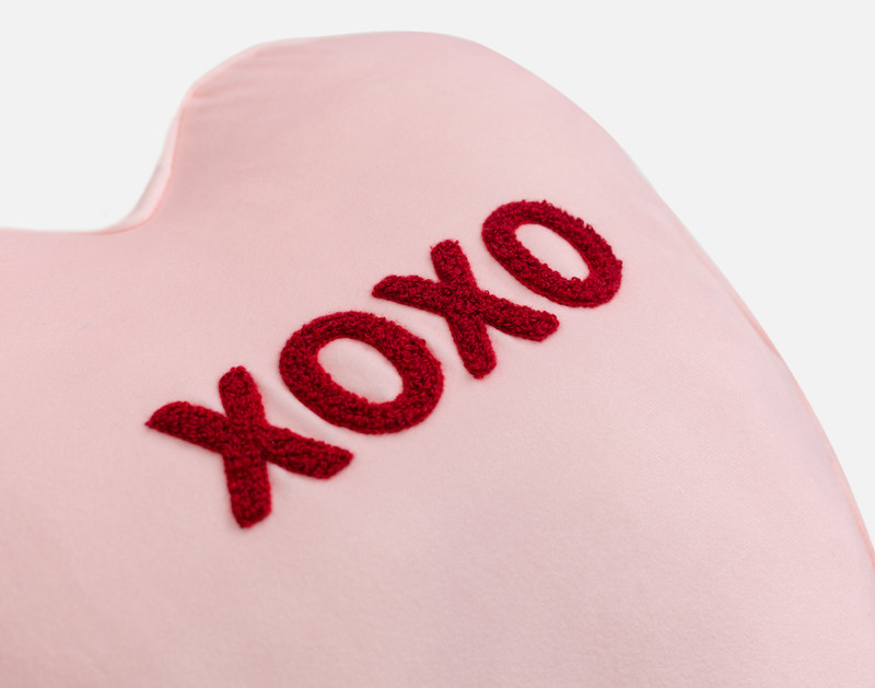 Angled view of our XOXO Candy Heart Cushion, named after the text written in tufted embroidery on its center.