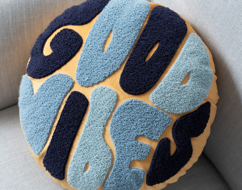 Close-up on the tufted lettering on our round Good Vibes BeaYOUtiful Cushion.