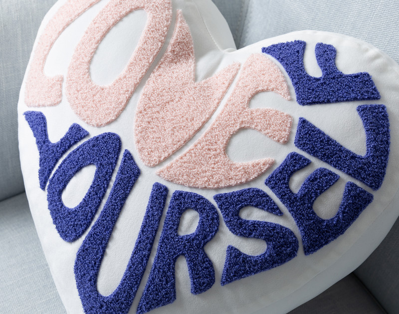 Close-up on the tufted lettering on our heart-shaped Love Yourself BeaYOUtiful Cushion.