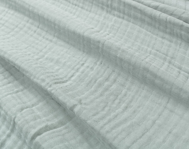 Close-up on our Seagrass Muslin Gauze Blanket to show its subtle grid-like texture and extra soft surface.