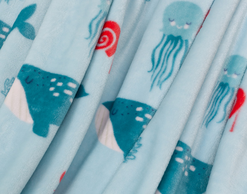 Close-up on the whales and jellyfish on the surface of our Whaley Kids' Fleece Velveteen Throw.