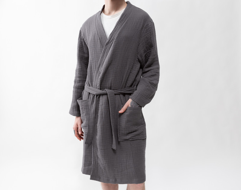 Closer view of a man wearing our Muslin Gauze Bathrobe in Charcoal with the wearer's hands in the robe's long pockets.