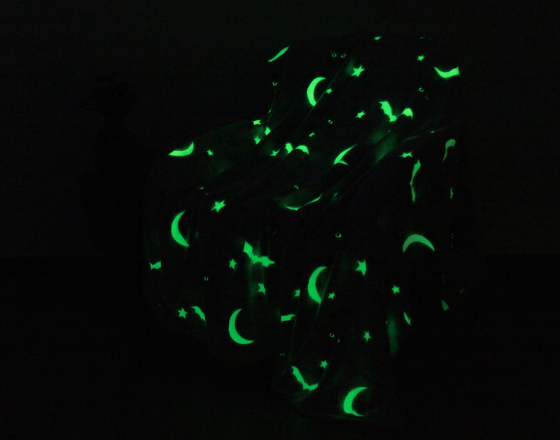 Our Peek-A-Boo Glow in the Dark Fleece Throw in a  dark room to show its gentle green glowing design.