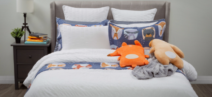 Front view of a bed dressed in our Kailua white duvet cover and Forest Friends cotton quilt set, with adorable plush fox and moose cushions over the foot.
