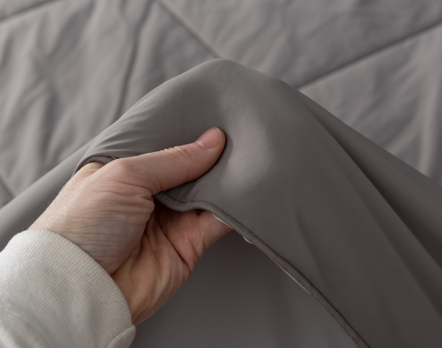 Hand feeling the edge of our Granite Cool Touch Blanket's soft surface.