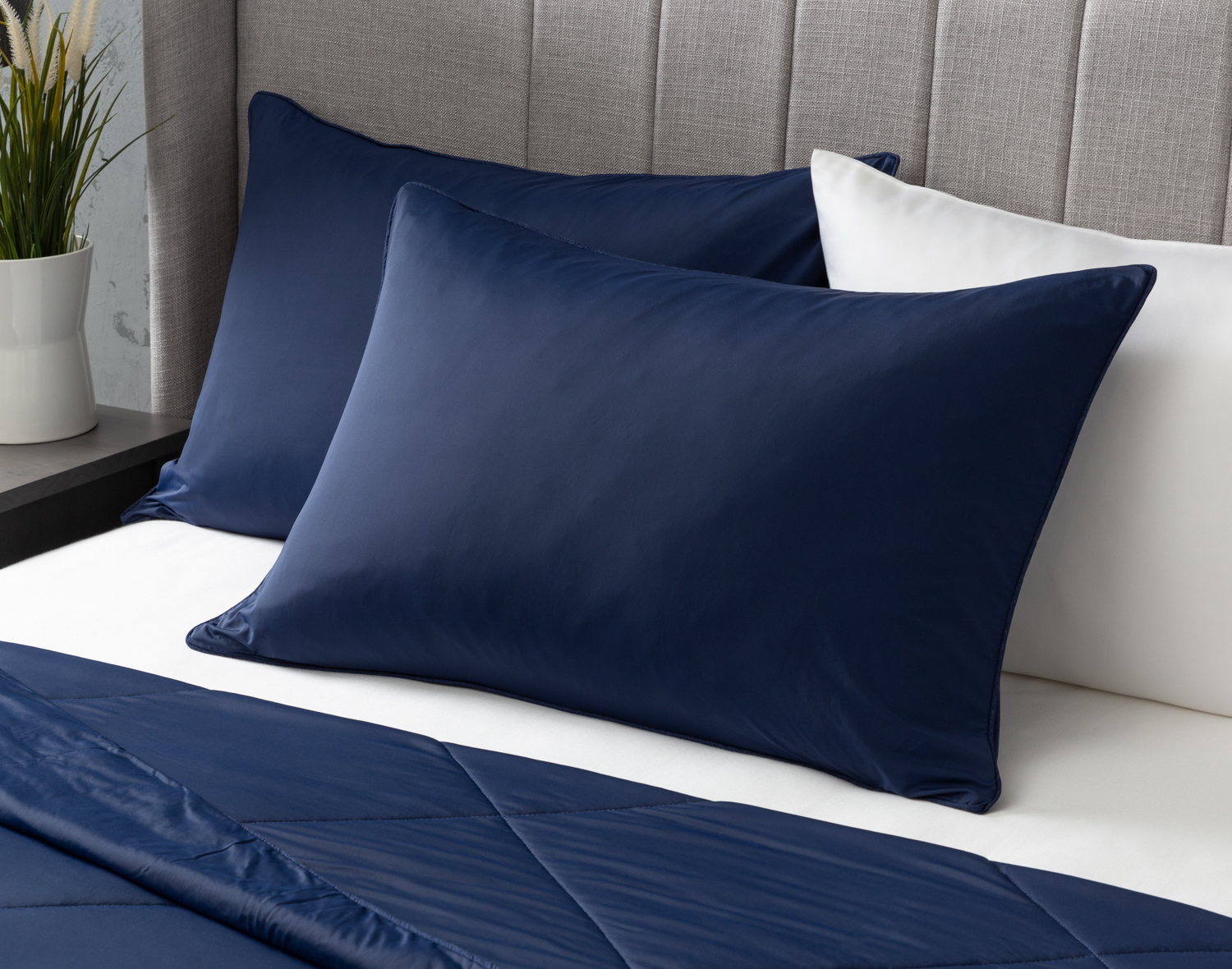 Angled view of two Midnight Cool Touch Pillowcase sitting at the head of a white bed.