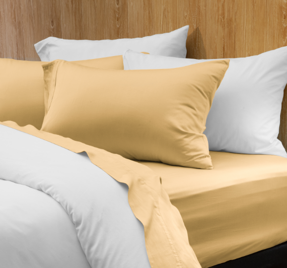 Notre Eucalyptus Luxe drap ensemble  en jaune canari habillé sur un lit blanc dans une chambre en bois.