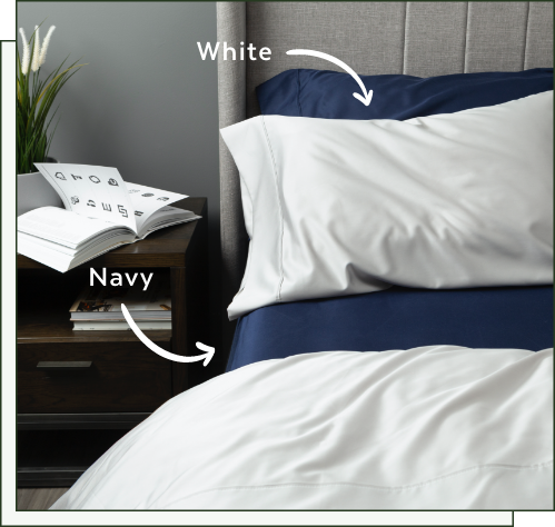 Our Eucalyptus Luxe TENCEL™ Lyocell Sheets in White and Navy dressed over a bed in a neutral bedroom.