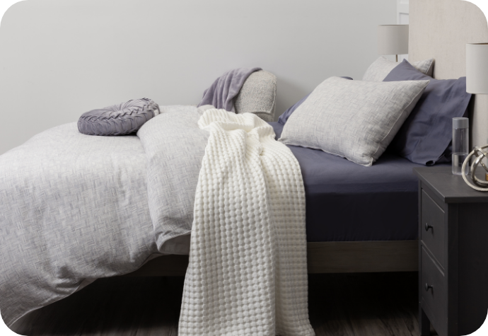 Landon Duvet Cover dressing a bed complete with matching pillow shams, blue sheets, and a throw blanket and cushion.