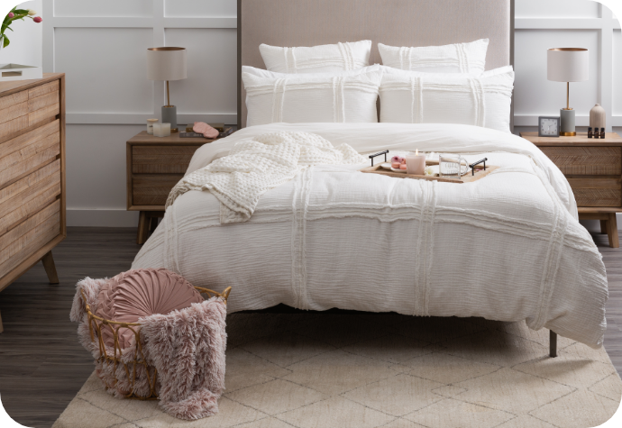 Lavish cotton jacquard duvet cover with matching pillow shams in white and accessorized with throw blankets on a queen bed in a trendy wooden bedroom.