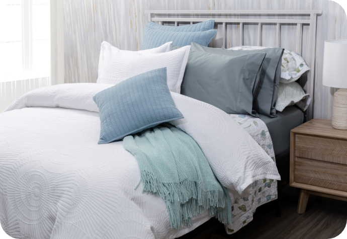 The Boca Duvet Cover and matching pillow shams dressing a queen bed with muted blue sheets, blue pillows and a blue throw.
