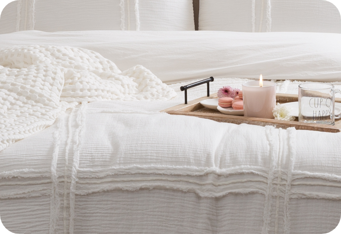 Lavish cotton jacquard duvet cover with matching pillow shams in white and accessorized with a throw blanket on a queen bed with a classy tea and cookie tray.