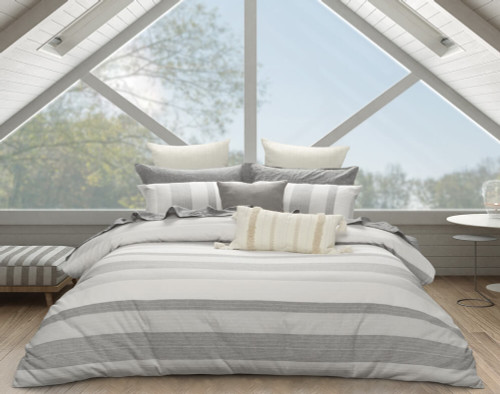 Our Oslo Duvet Cover dressed with textured white & beige accessory pillows in a wide windowed bedroom during a sunny day.
